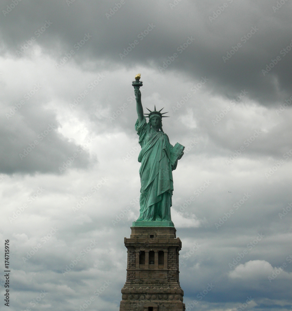 Statue of liberty seen from the front with a grey and cloudy sky as background in Manhattan, New York City.