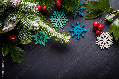 Background christmas decoration twig, red berries and wooden stars on back slate.