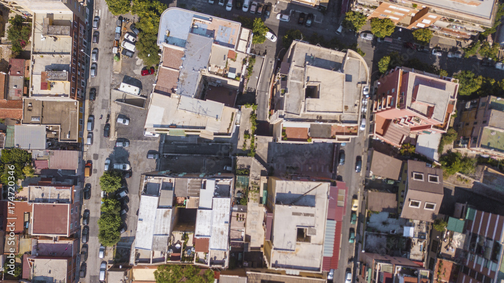 Fototapeta premium Vista aerea perpendicolare dei tetti di alti palazzi adibiti ad uso residenziale in una grande città italiana. Le automobili e le persone dall'alto sembrano molto piccoli.