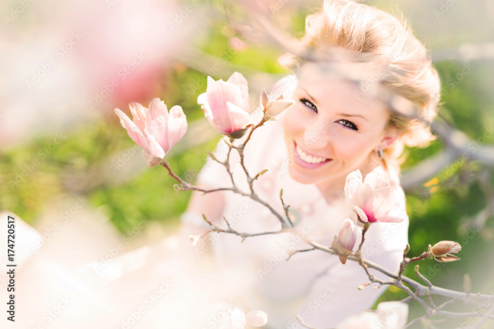Beautiful Woman smiling among magnolia flowers Beautiful Woman smiling among magnolia flowers