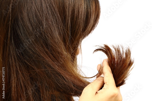Woman holding her long hairs that make color treatments. The hairs maybe have problem (split end) .Should care or cut end of hairs. On white background