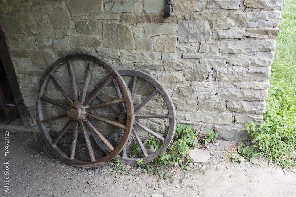 Wooden wheels leaning against a stone wall.