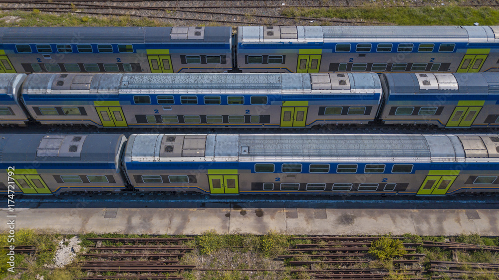 Vista aerea di tre treni fermi con tutti i vagoni al deposito ferroviario.  Sono vecchi, abbandonati e siccome in disuso da tempo non corrono più.  Stock Photo | Adobe Stock