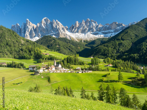 Colors of Dolomites. funes view of the valley  Puez-Odle in autumn. at sunset holy magdalena. View of odle mountain. Santa Maddalena  Tyrol  Italy. Green grass  mountains and blue sky. Summer