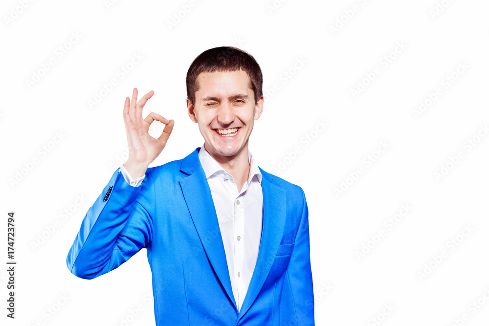 Closeup isolated portrait of young man in blue suit showing OK gesture at white background. Closeup isolated portrait of young man in blue suit showing OK gesture at white background.