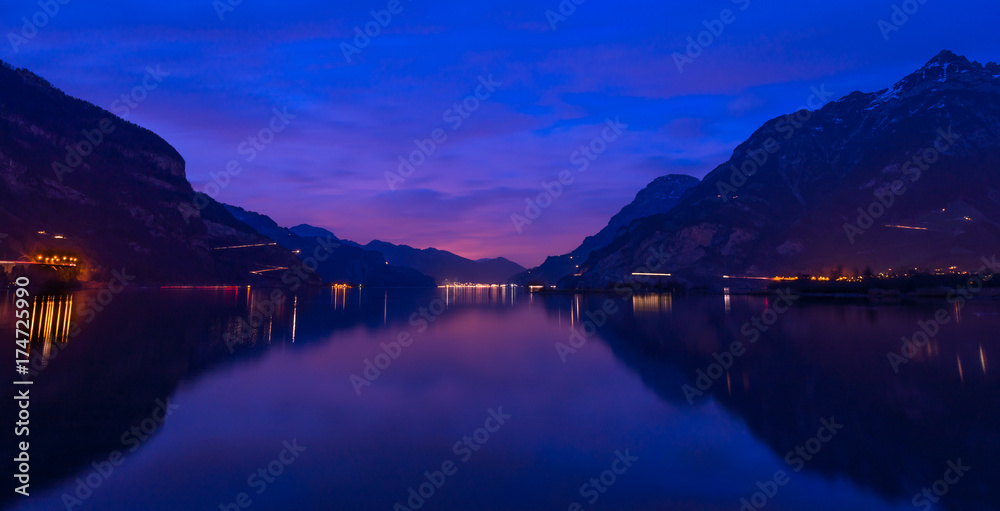 Central Switzerland, Lake Lucerne. Night landscape. Royal blue. The mountain range, the light of lanterns and lamps are reflected in the lake, long exposure
