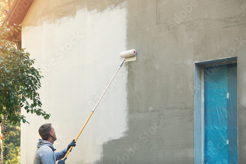 Fotografi house painter painting building exterior with roller