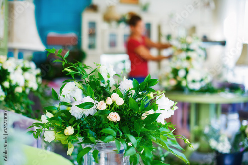 Flowers arrangement bouquets as decoration for wedding, silhouette of florist woman at work out of focus on background © Zoja
