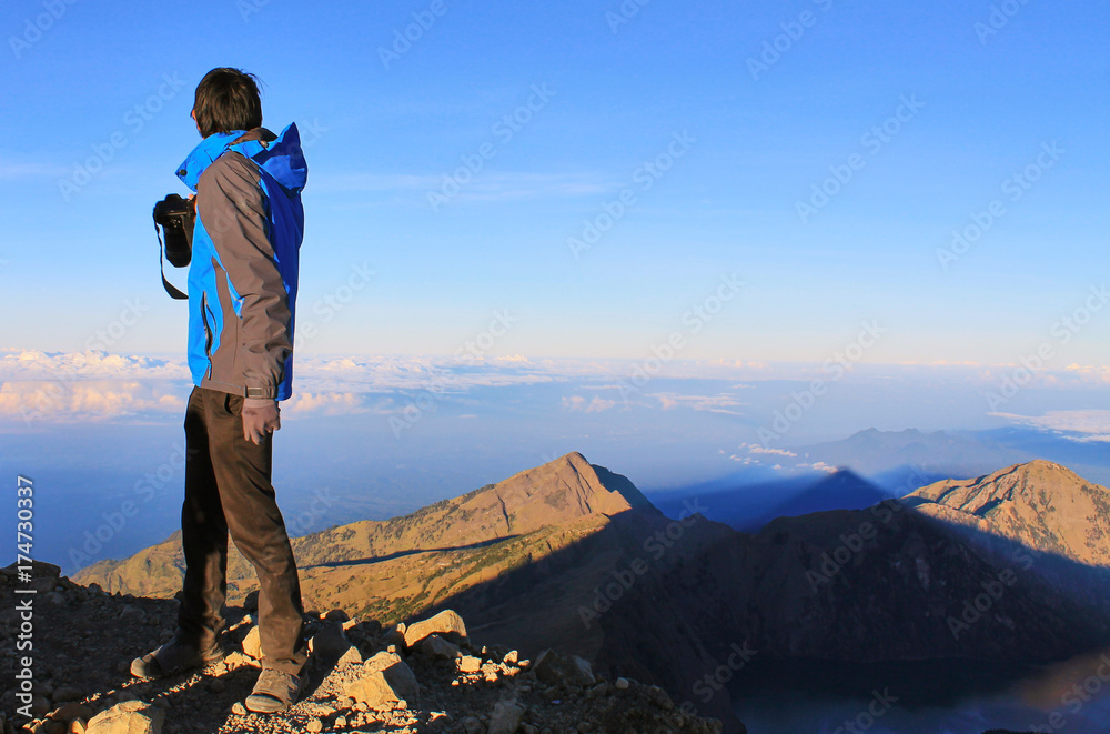 Traveler is seeing and taking a photograph of Rinjani Summit at sunset time. Mountain Rinjani at Lombok, Indonesia.