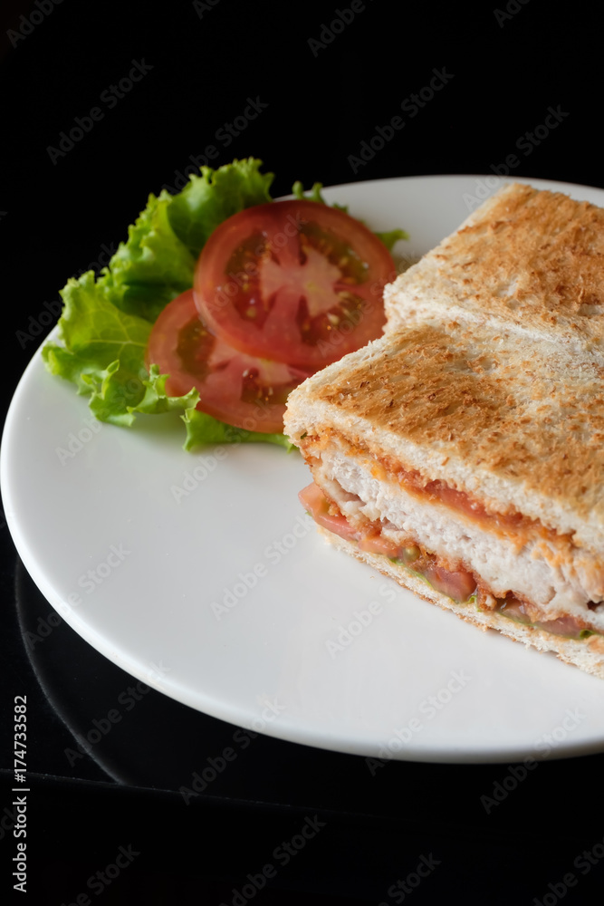 Close up healthy sandwich toast with lettuce, fried pork, cheese and tomato on a black marble background.
