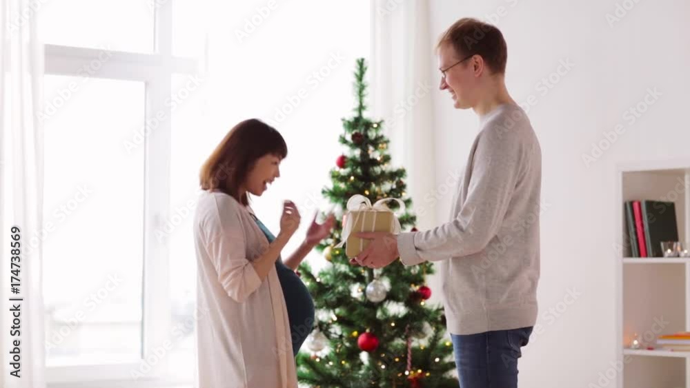 husband giving christmas present to pregnant wife husband giving christmas present to pregnant wife