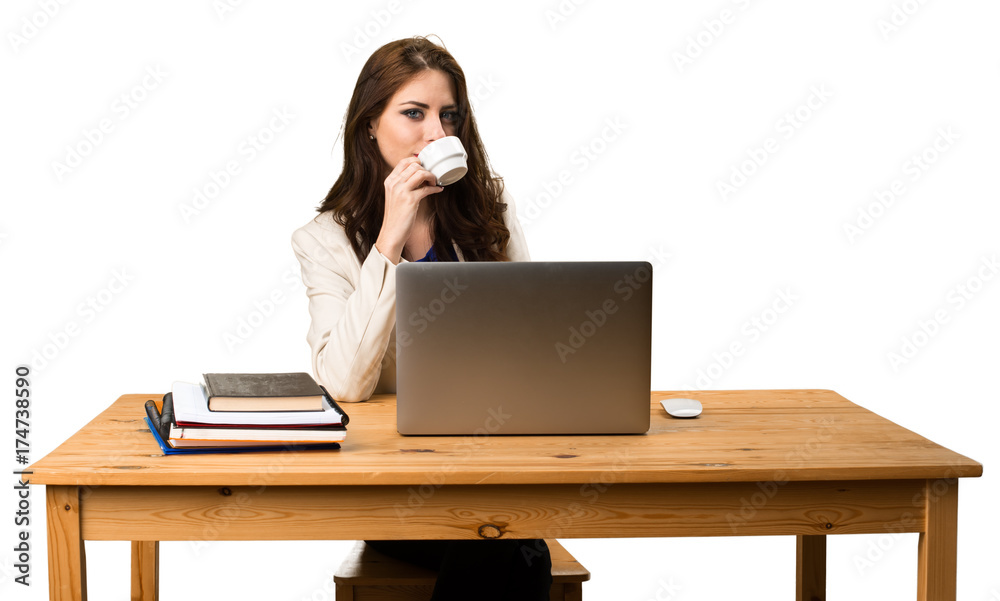 Business woman working with her laptop and holding a cup of coffee Business woman working with her laptop and holding a cup of coffee