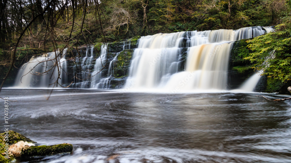 Long exposure of a waterfall (Sgwd Y Pannwr) in a tree covered forest in the autumn Long exposure of a waterfall (Sgwd Y Pannwr) in a tree covered forest in the autumn