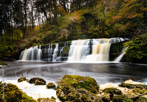 Long exposure of a waterfall (Sgwd Y Pannwr) in a tree covered forest in the autumn