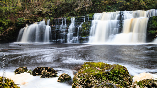 Long exposure of a waterfall  Sgwd Y Pannwr  in a tree covered forest in the autumn
