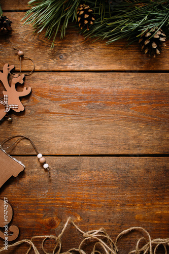 Christmas and New Year holiday background. Close up handmade ornaments of skate and deer on left and pine with strobila above on wooden table, festive decoration concept. Free space in the middle photo