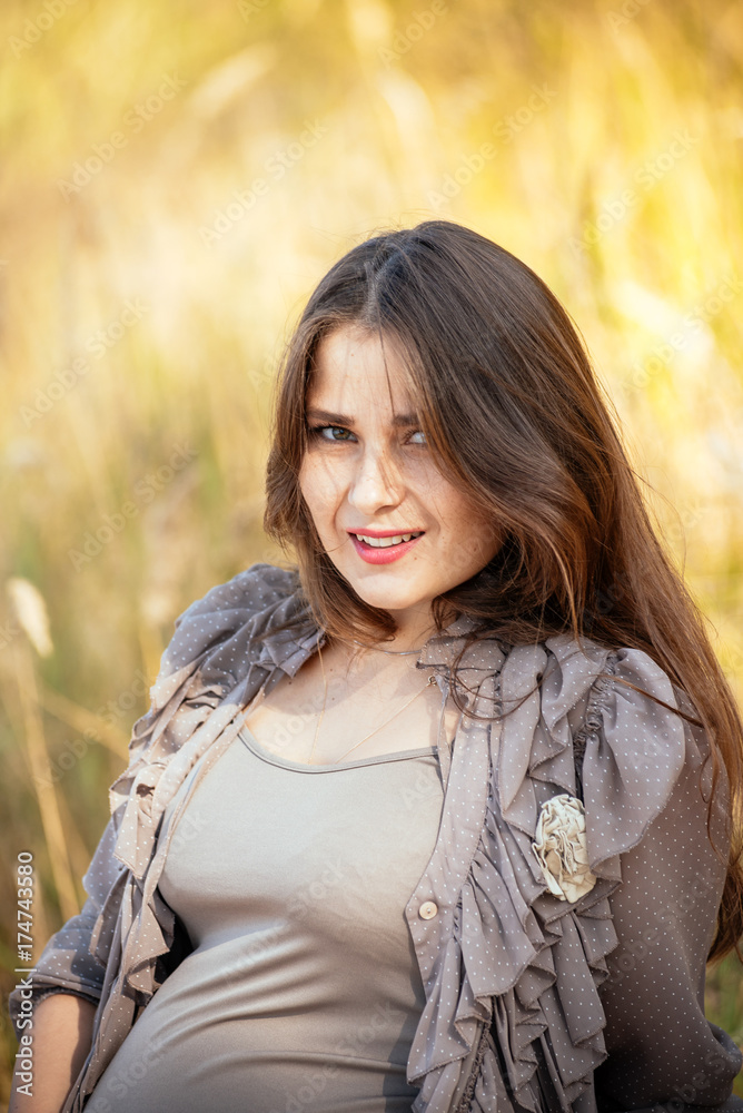 portrait of a beautiful pregnant young girl against a background of autumn forest. In fashionable clothes. Photo concept of pregnant women portrait of a beautiful pregnant young girl against a background of autumn forest. In fashionable clothes. Photo concept of pregnant women