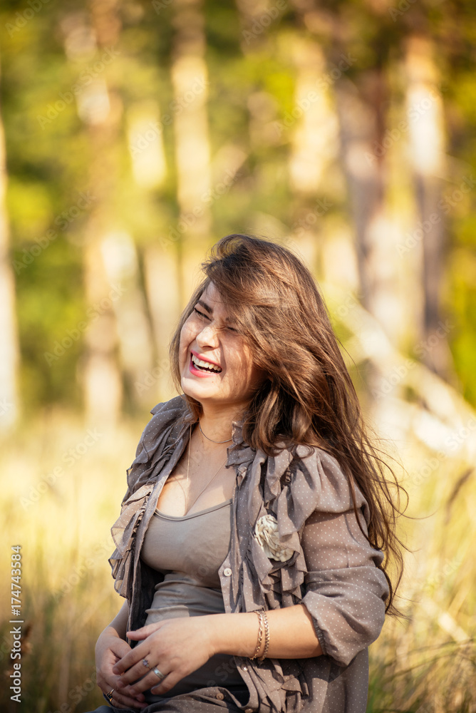 portrait of a beautiful young pregnant girl in a trendy dress against the background of an autumn forest