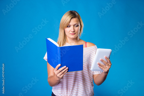 Blonde woman choosing between book and tablet