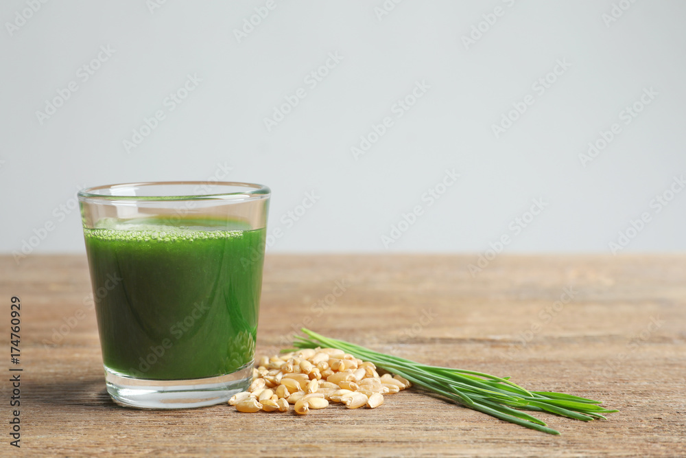 Wheat grass shot and grain on wooden table Wheat grass shot and grain on wooden table