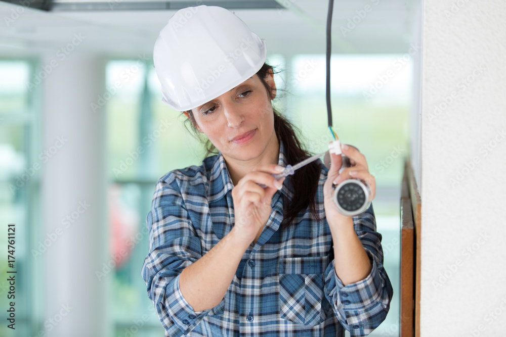 young female technician installing surveillance camera on ceiling young female technician installing surveillance camera on ceiling