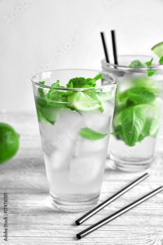 Cold fresh mojito with mint and lime slices in glass on wooden background