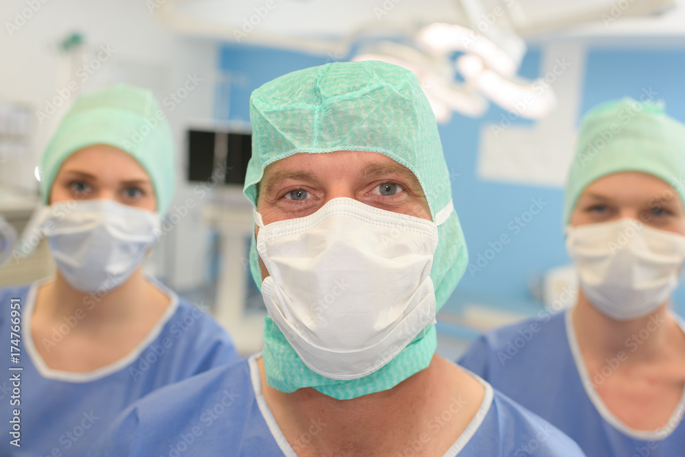three surgeons at work operating in surgical theatre three surgeons at work operating in surgical theatre