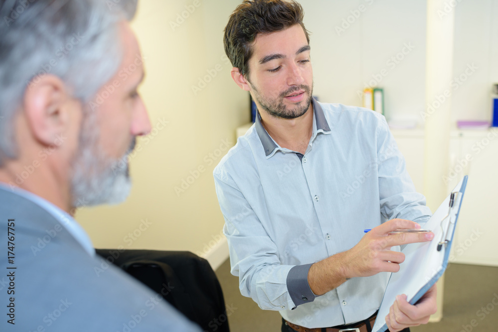 Obraz premium happy coworkers enjoying a conversation one is holding a clipboard