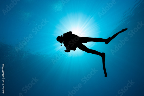 Silhouette of a SCUBA diver with sunburst behind