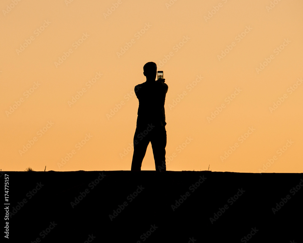A man taking selfie on sunset