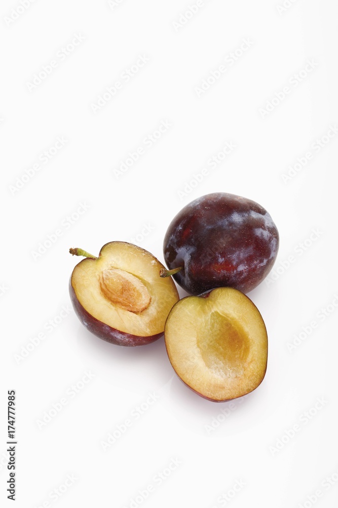 Fototapeta premium Two plums, one of them halved