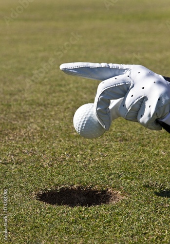 Putting without golf clubs, hand holding a golf ball photo