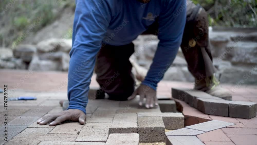 Very tight shot of stone mason fitting brick pavers into a patio design. Very tight shot of stone mason fitting brick pavers into a patio design.