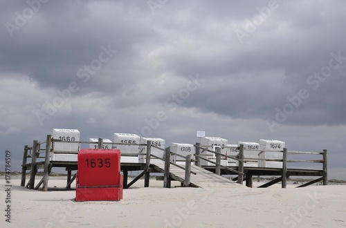 Roofed wicker beach chairs on a platform on stilts, beach on the North Sea, St. Peter-Ording, Schleswig-Holstein, Germany, Europe photo