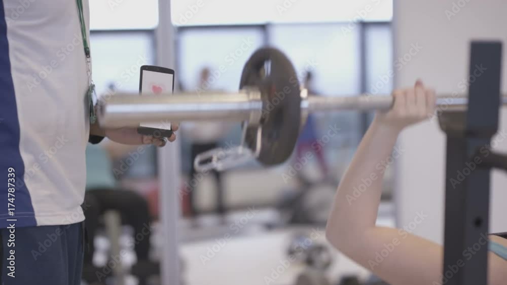 Fitness Trainer Using Smartphone App To Train With A Client At The Gym Fitness Trainer Using Smartphone App To Train With A Client At The Gym