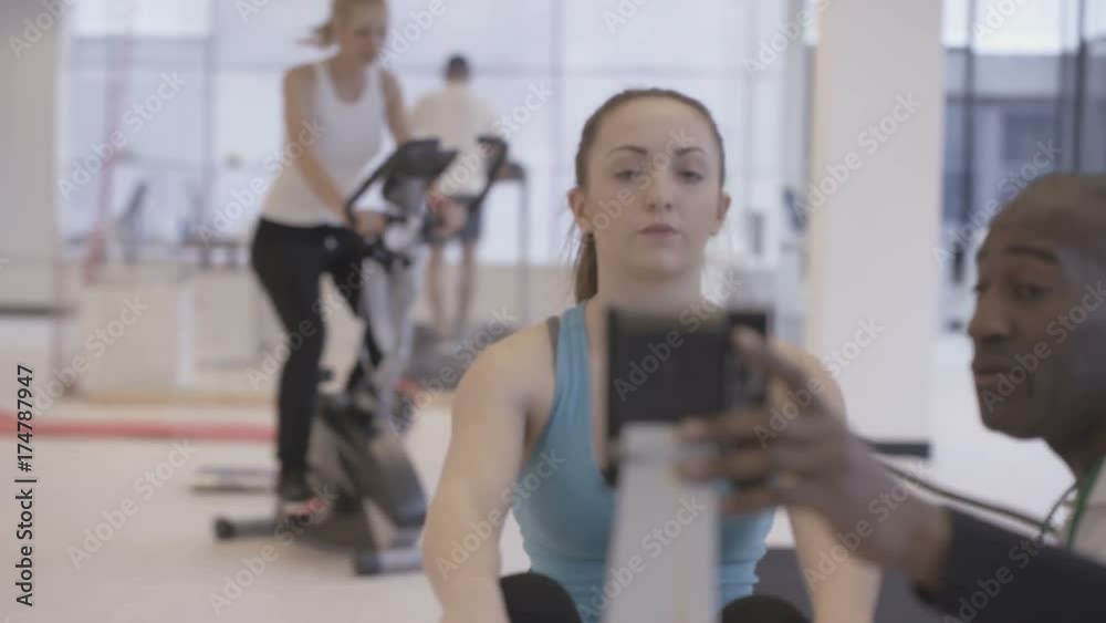 Young fit group working out in the gym with fitness instructor supervising Young fit group working out in the gym with fitness instructor supervising