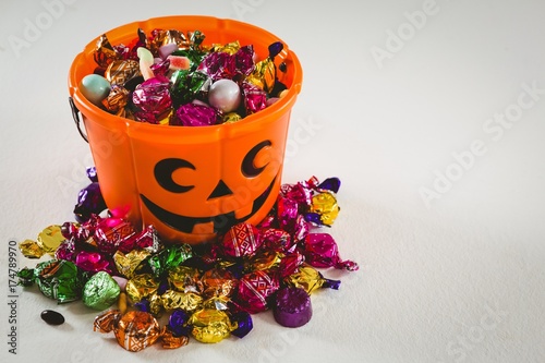 Bucket with various sweet food over white background during