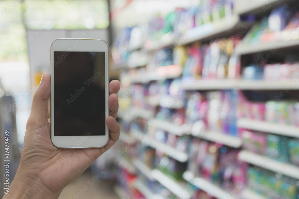 Woman hand holding smart phone in super market shopping blur background. Woman hand holding smart phone in super market shopping blur background.