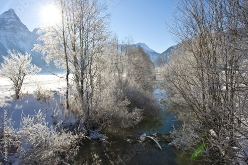 Small brook with thick snow-covered trees between the towns of Ehrwald and Lermoos, Tyrol, Austria, Europe photo