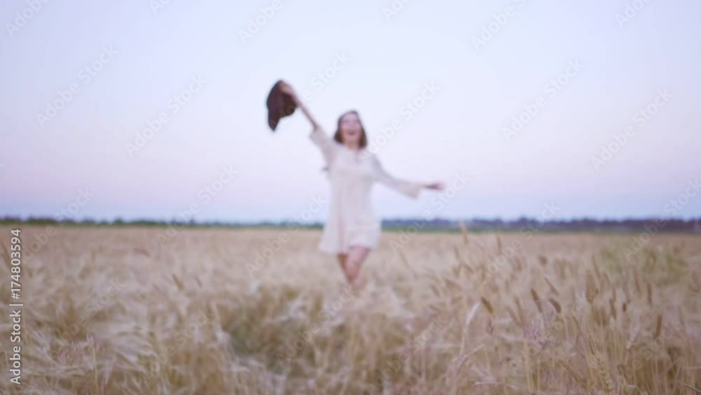 Blur view of young happy woman in white dress running in the field and waving her hat Blur view of young happy woman in white dress running in the field and waving her hat