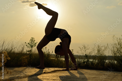 A woman practices yoga on a background of mountains and sky. Toned
