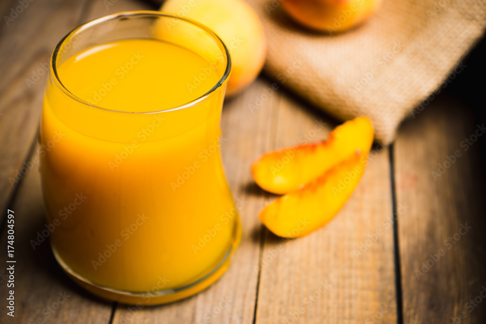 Glass of peach juice with fresh peaches on the rustic background. Shallow depth of field. Glass of peach juice with fresh peaches on the rustic background. Shallow depth of field.