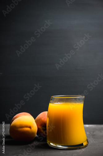 Glass of peach juice with fresh peaches on the rustic background. Shallow depth of field.