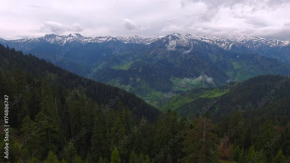 Aerial view of the mountain valley in magic evening after storm - flight over green hills covered with huge fir trees, mountain villages, pastures and alpine meadows. Aerial view of the mountain valley in magic evening after storm - flight over green hills covered with huge fir trees, mountain villages, pastures and alpine meadows.