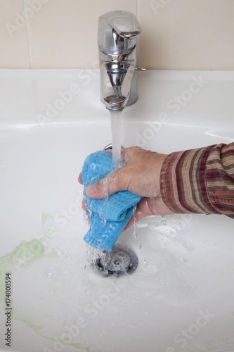 Sink being cleaned, running tap water, hand washing out sponge cloth photo