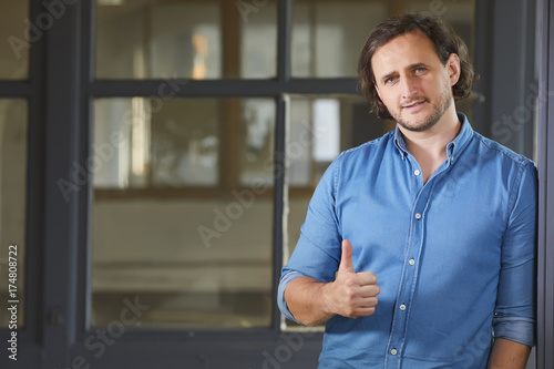 Portrait of a cheerful young man showing okay gesture on the old window background