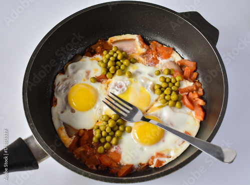 Eggs with tomatoes and green peas in a frying pan