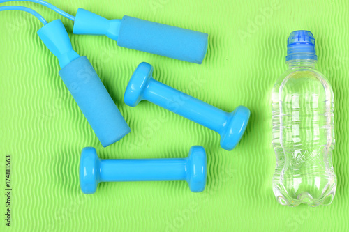 Barbells and skipping rope next to water bottle