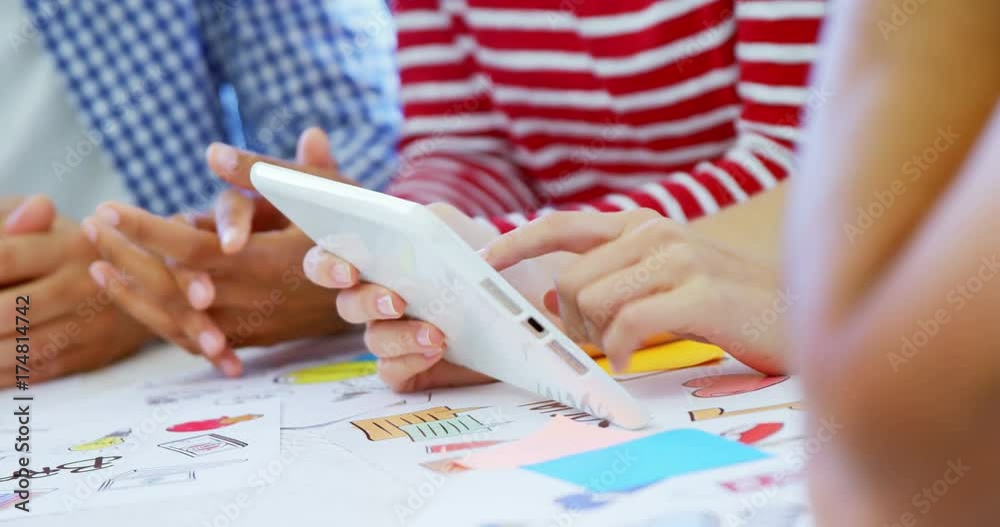 Colleagues discussing over digital tablet at table 