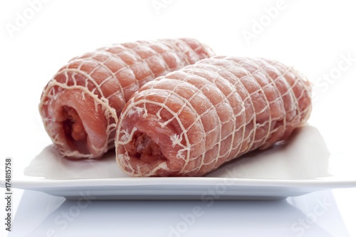 Raw pork roulade in a net on a porcelain plate